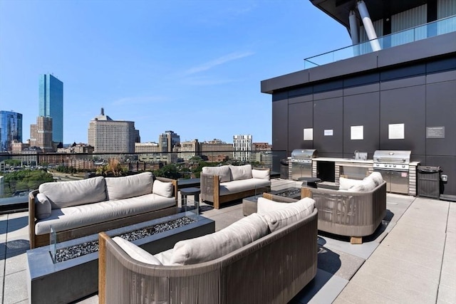 view of patio / terrace featuring an outdoor living space with a fire pit, exterior kitchen, a view of city, and grilling area