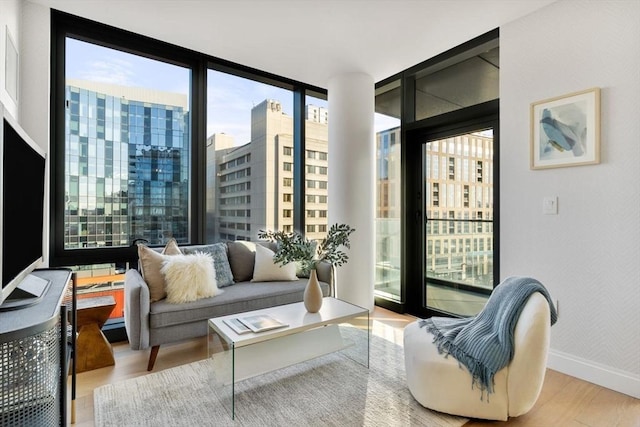 interior space with a view of city, a wall of windows, baseboards, and wood finished floors