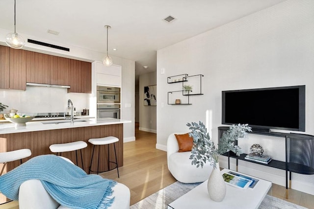 living room featuring visible vents, baseboards, and light wood-style flooring