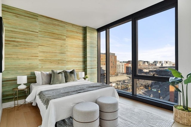 bedroom featuring a city view, wood finished floors, and expansive windows