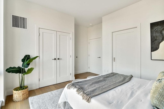 bedroom featuring visible vents, baseboards, a closet, and wood finished floors