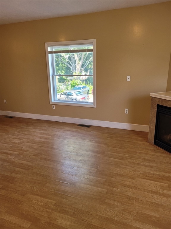 unfurnished living room with light hardwood / wood-style floors and a tiled fireplace