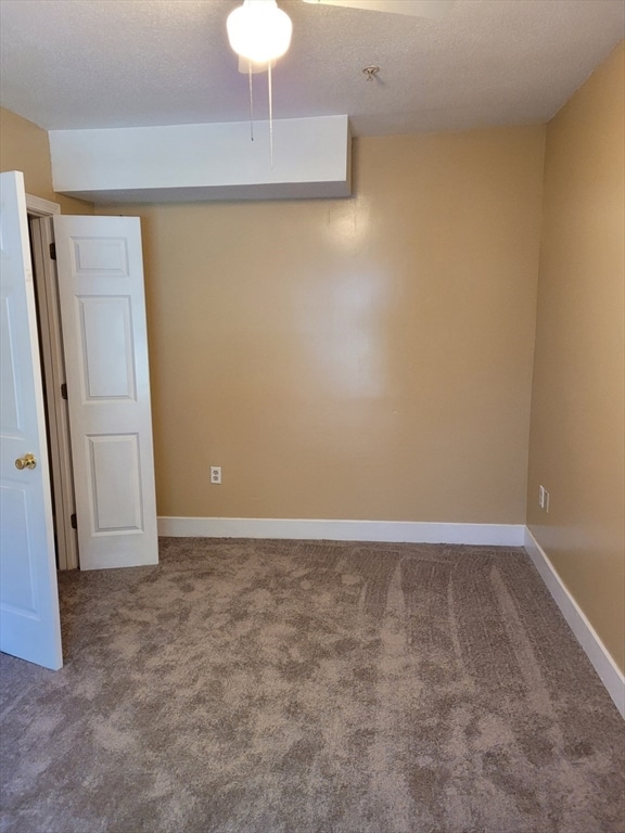 carpeted empty room featuring a textured ceiling