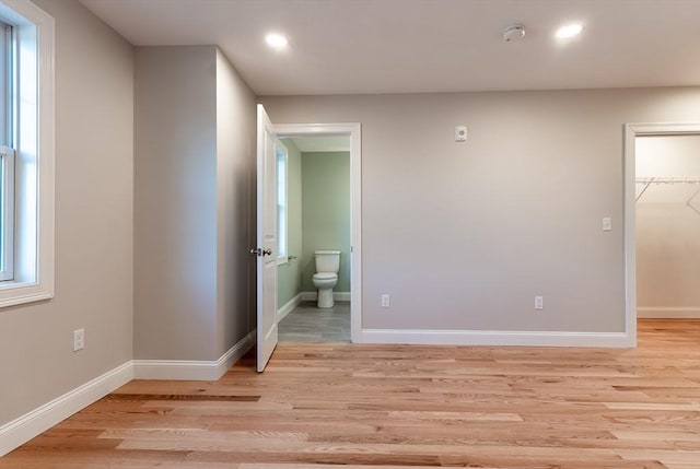 unfurnished bedroom with light hardwood / wood-style floors, a walk in closet, and a closet