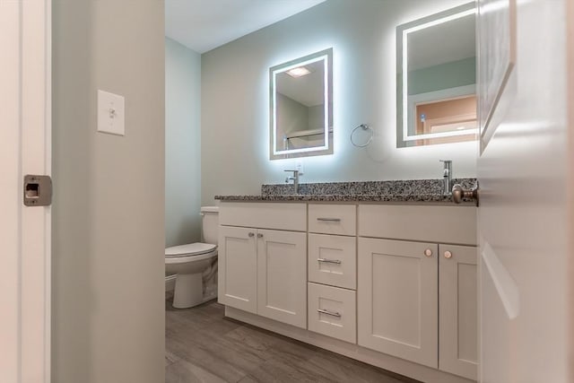 bathroom featuring vanity, hardwood / wood-style flooring, and toilet