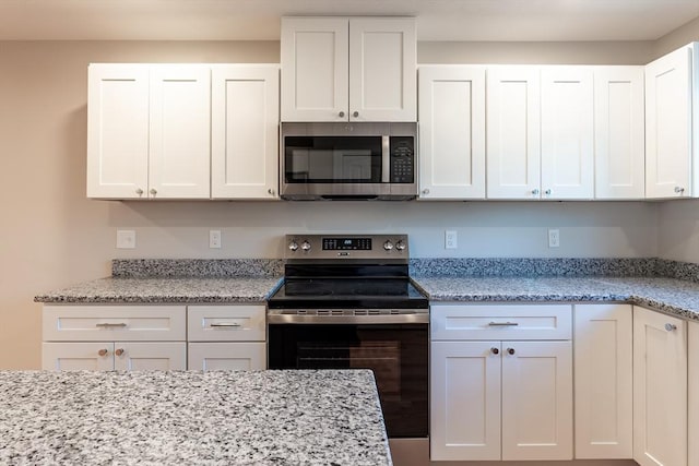 kitchen with light stone counters, white cabinetry, and appliances with stainless steel finishes