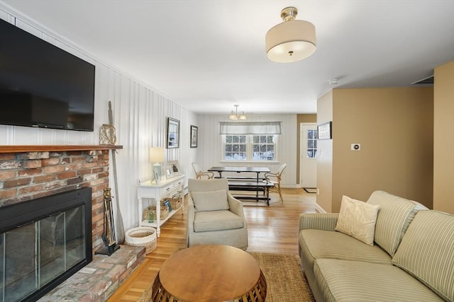 living room with a brick fireplace and light wood-type flooring