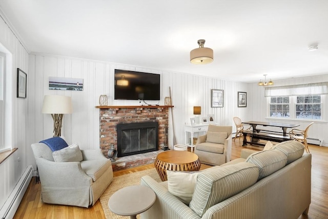 living room featuring an inviting chandelier, a brick fireplace, light hardwood / wood-style floors, and baseboard heating