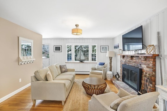 living room with a wealth of natural light, a fireplace, baseboard heating, and light hardwood / wood-style flooring