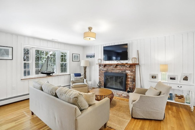 living room with a baseboard radiator, light hardwood / wood-style floors, and a brick fireplace