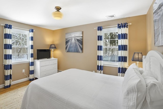 bedroom featuring multiple windows and light hardwood / wood-style flooring