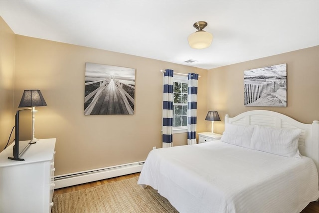 bedroom featuring wood-type flooring and a baseboard heating unit