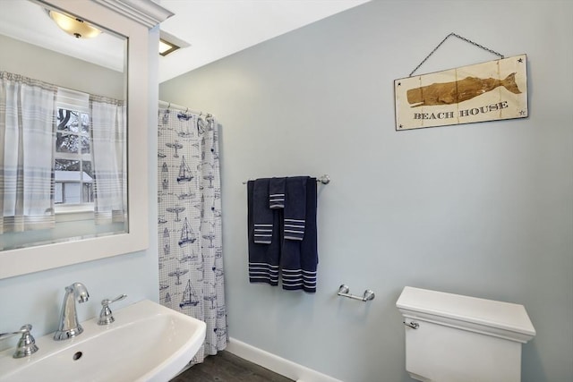 bathroom with sink, a shower with shower curtain, and toilet