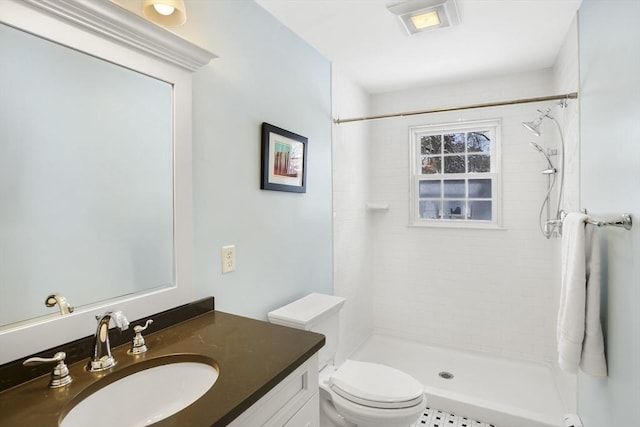 bathroom with tiled shower, vanity, and toilet