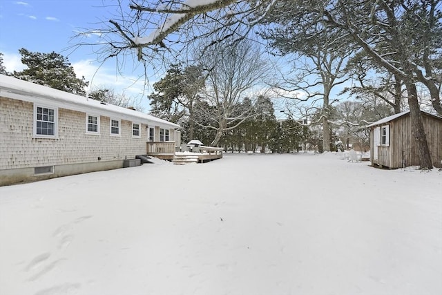 yard covered in snow with a storage unit and a deck