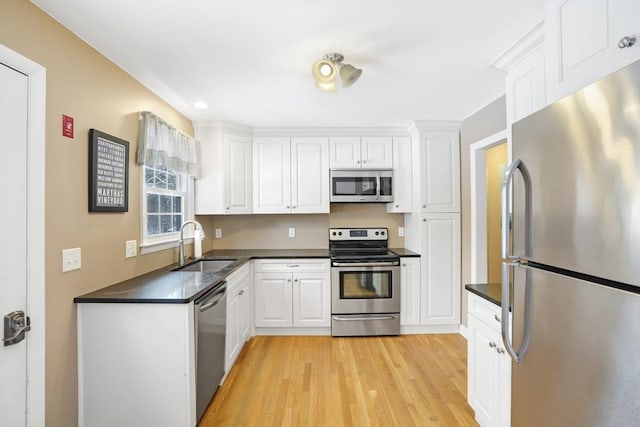 kitchen featuring appliances with stainless steel finishes, light hardwood / wood-style floors, sink, and white cabinets