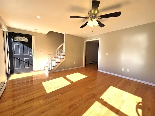 interior space featuring baseboard heating, ceiling fan, and hardwood / wood-style flooring