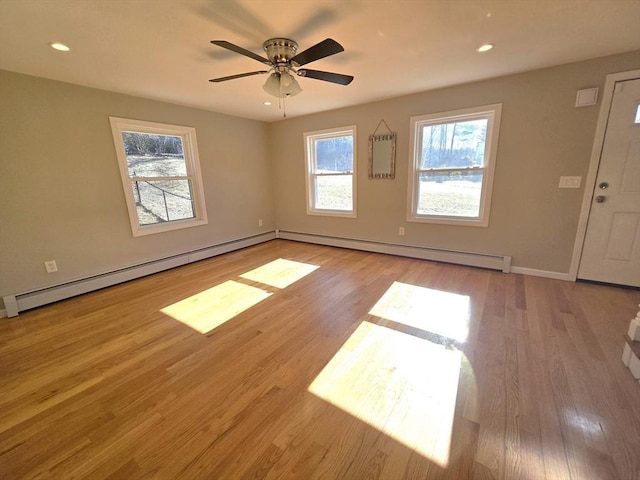 spare room featuring ceiling fan, light hardwood / wood-style flooring, and a baseboard heating unit