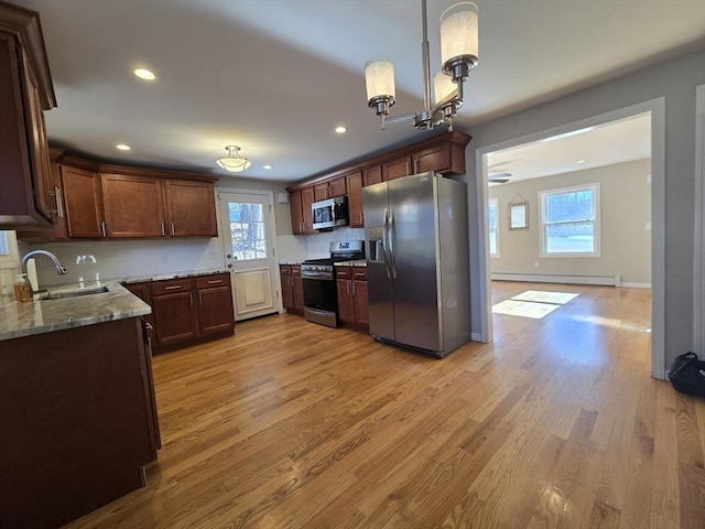 kitchen featuring hanging light fixtures, appliances with stainless steel finishes, sink, and light hardwood / wood-style flooring