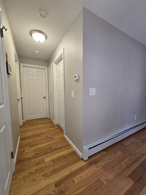 corridor featuring a baseboard heating unit and hardwood / wood-style floors