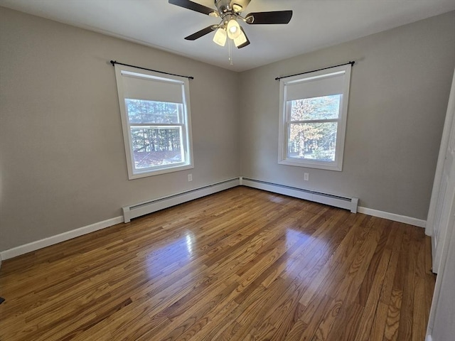 empty room featuring a baseboard heating unit, wood-type flooring, and ceiling fan