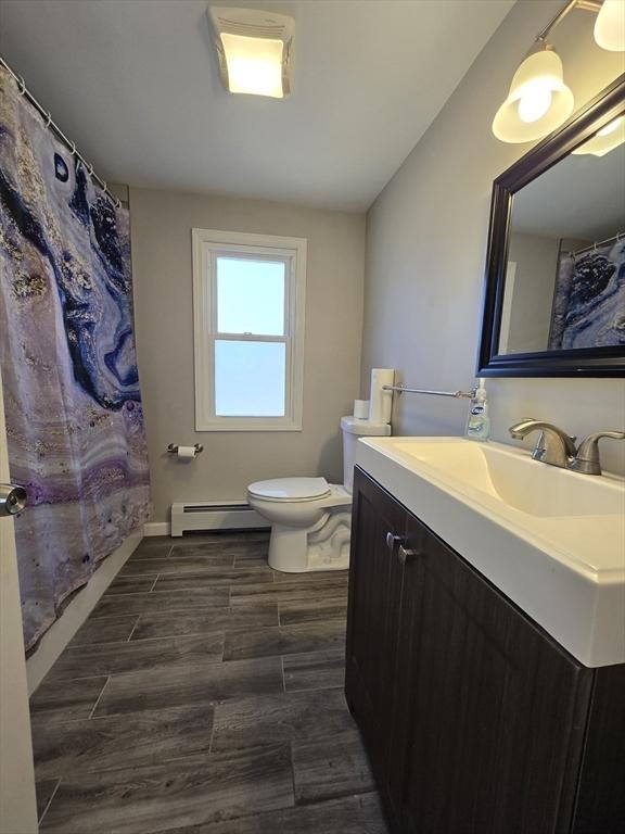 bathroom featuring walk in shower, a baseboard radiator, vanity, and toilet