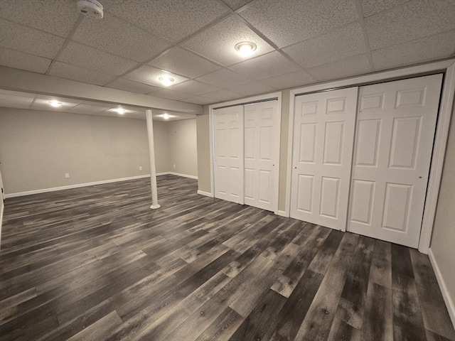 basement with a drop ceiling and dark hardwood / wood-style flooring