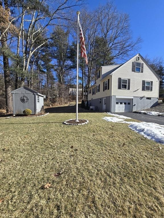 view of home's exterior featuring a garage, a storage unit, and a lawn