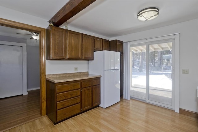 kitchen featuring freestanding refrigerator, light countertops, beamed ceiling, and light wood-style flooring