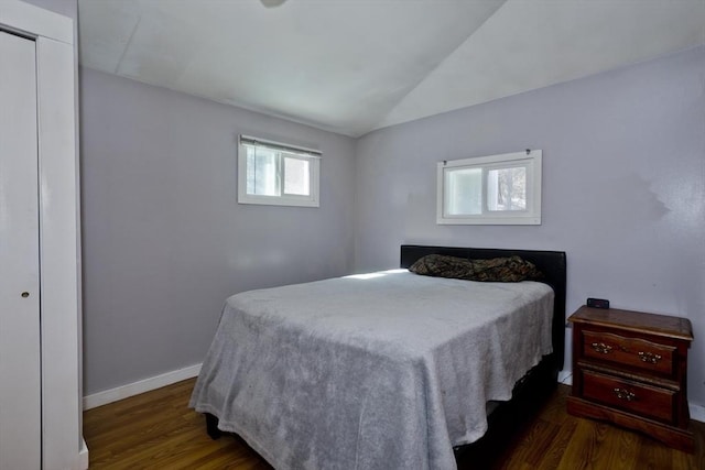 bedroom featuring lofted ceiling, a closet, baseboards, and wood finished floors