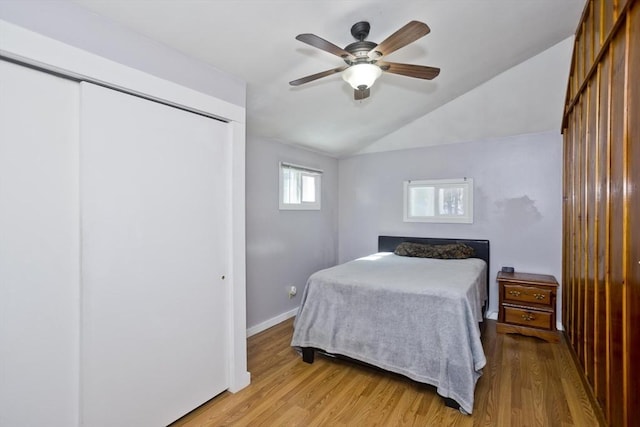 bedroom featuring baseboards, a ceiling fan, lofted ceiling, light wood-type flooring, and a closet