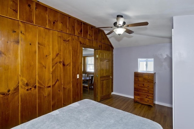 unfurnished bedroom featuring dark wood finished floors, multiple windows, vaulted ceiling, and baseboards