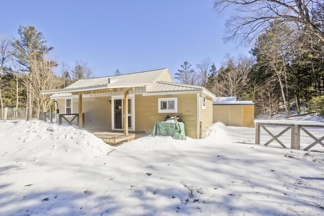 snow covered rear of property featuring covered porch and metal roof