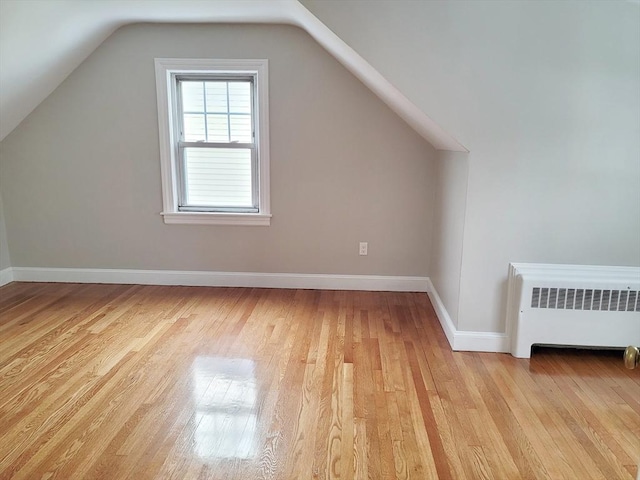 bonus room with lofted ceiling, radiator heating unit, and light hardwood / wood-style flooring