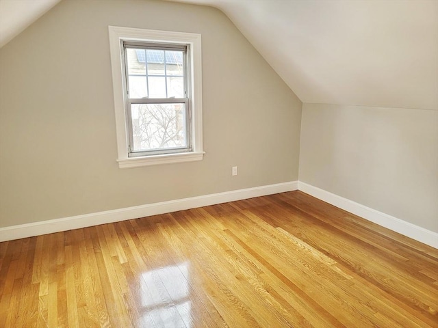 additional living space with hardwood / wood-style flooring and vaulted ceiling