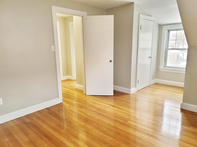 empty room with vaulted ceiling and light hardwood / wood-style floors