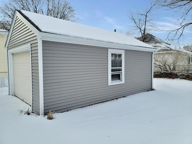 snow covered property featuring a garage and an outbuilding