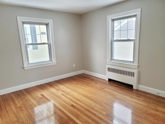 spare room featuring radiator and light wood-type flooring