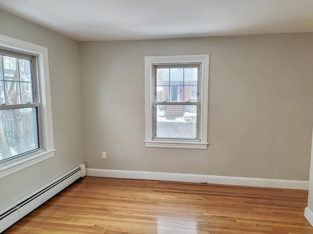 empty room featuring a baseboard radiator, a wealth of natural light, and light hardwood / wood-style flooring