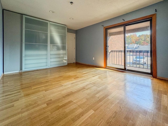 empty room featuring a textured ceiling and light hardwood / wood-style flooring