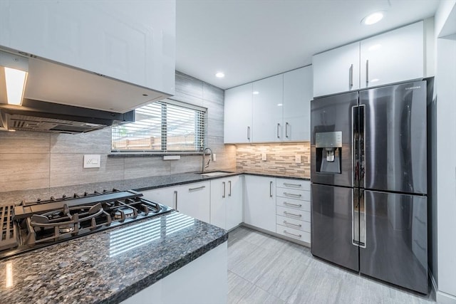 kitchen featuring cooktop, white cabinetry, dark stone counters, and stainless steel fridge