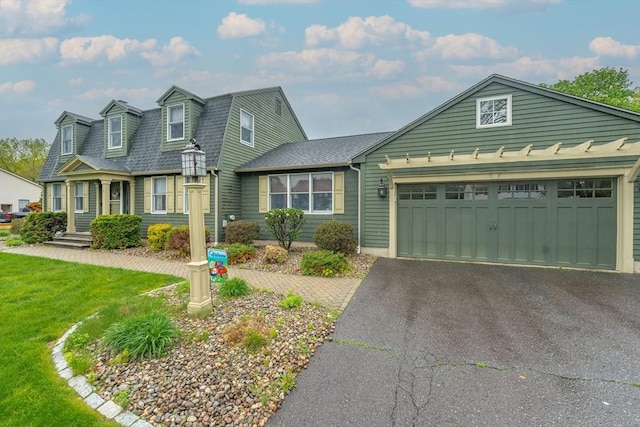 view of front facade featuring an attached garage, roof with shingles, a front yard, and aphalt driveway
