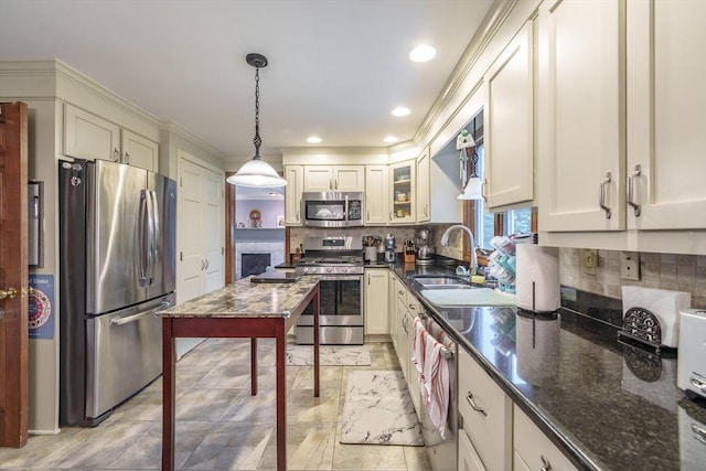 kitchen with a sink, backsplash, pendant lighting, and appliances with stainless steel finishes