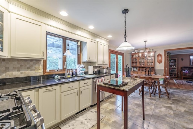 kitchen with hanging light fixtures, a sink, dark countertops, crown molding, and appliances with stainless steel finishes