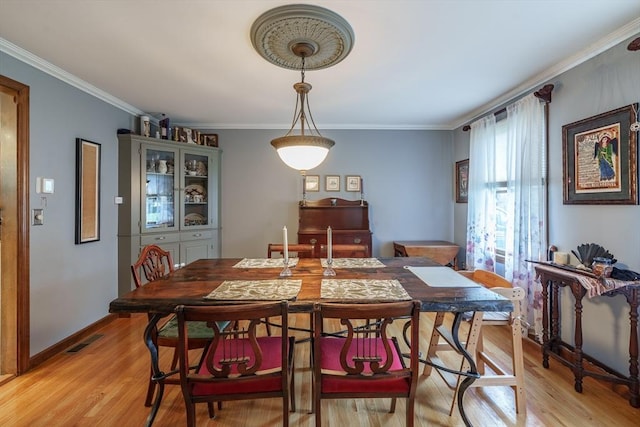 dining area featuring ornamental molding, light wood-style flooring, and visible vents