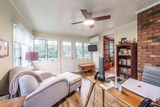 living room with a wall mounted air conditioner, wood finished floors, ornamental molding, ceiling fan, and baseboards