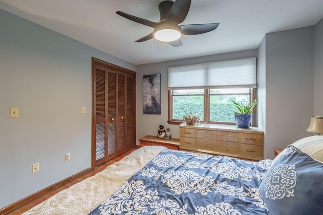 bedroom featuring a ceiling fan, baseboards, a closet, and wood finished floors