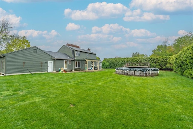 rear view of property featuring a lawn and a fenced in pool