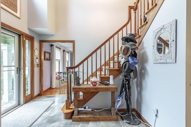 tiled entryway with stairway, baseboards, and a towering ceiling