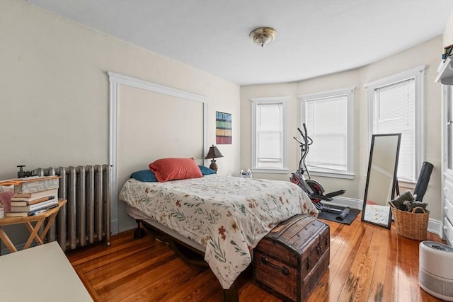 bedroom with wood-type flooring, baseboards, and radiator heating unit